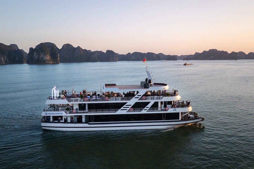A large white boat with multiple decks, people on the upper deck, and a calm water body with distant landforms. 2