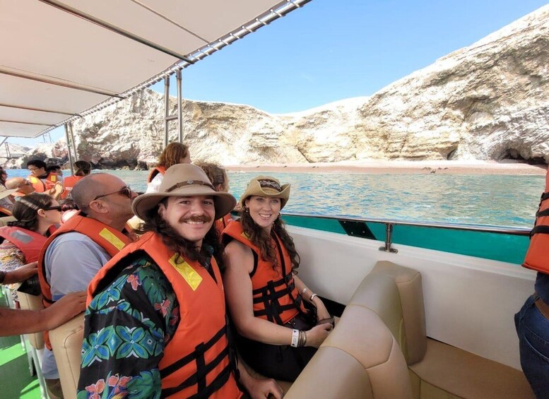 A boat with passengers wearing life jackets, rocky cliffs, and a beach in the background. 4