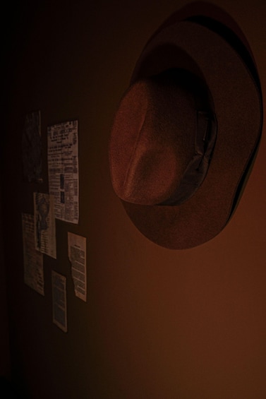 A cowboy hat hanging on a wall with several posters or notices attached to it. 2