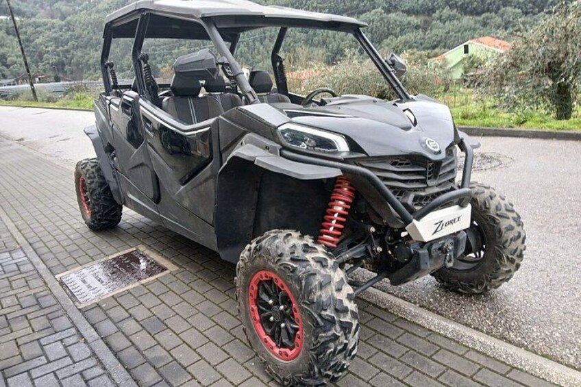 A four-wheeled vehicle with off-road tires and a raised suspension system, parked on a paved surface. 2