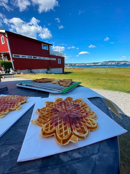 A table with waffles and a red building in the background. 1