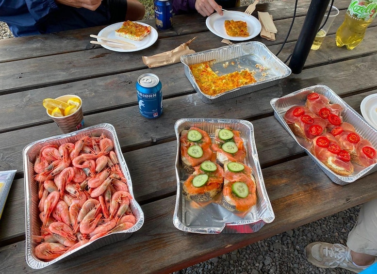 A picnic table with food items including shrimp, sandwiches, and a can of beer. 3