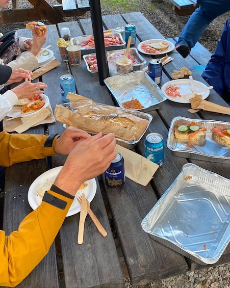 People sitting at a picnic table with food and drinks. 5