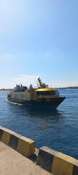 A yellow and black boat with people on board, docked at a pier. 1