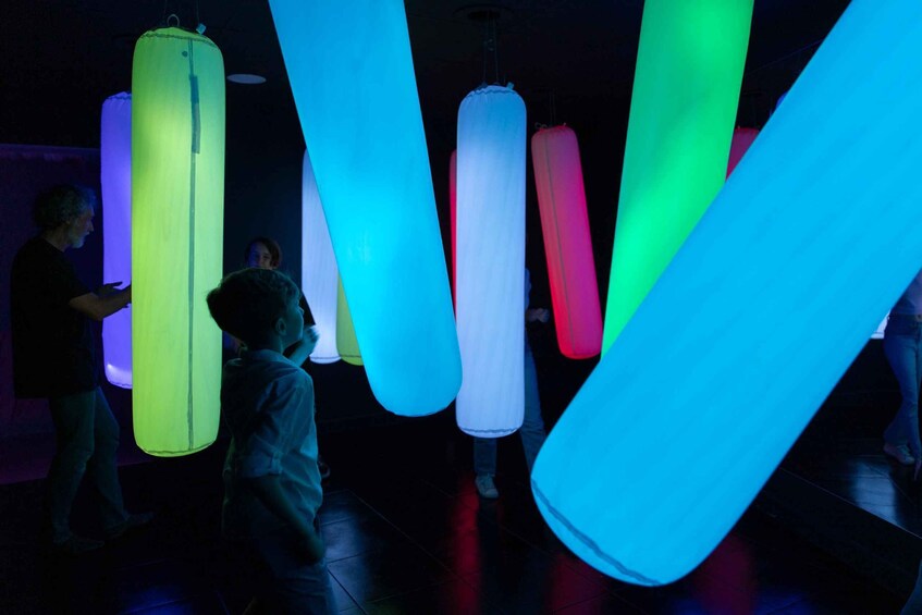People in a dimly lit room with illuminated cylindrical objects. 1
