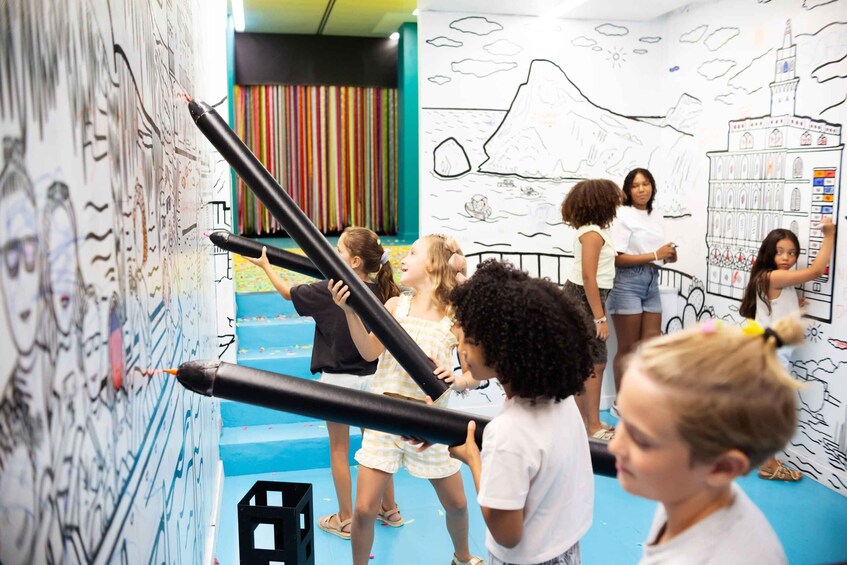 Children drawing on a wall with markers in a classroom setting. 5