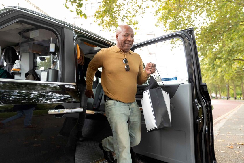 A man in a yellow shirt and jeans stepping out of a van. 2