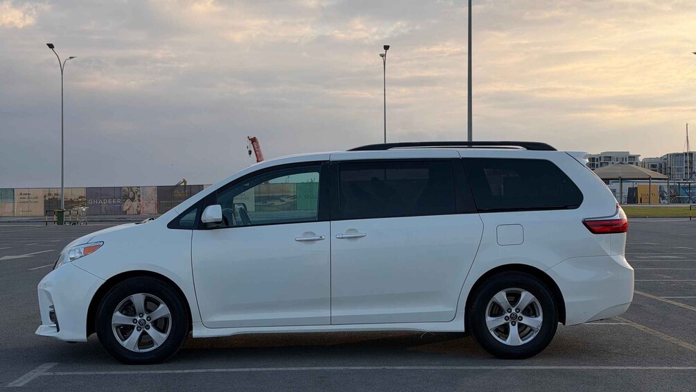 Una camioneta blanca estacionada en un estacionamiento, con un cielo nublado al fondo. 2