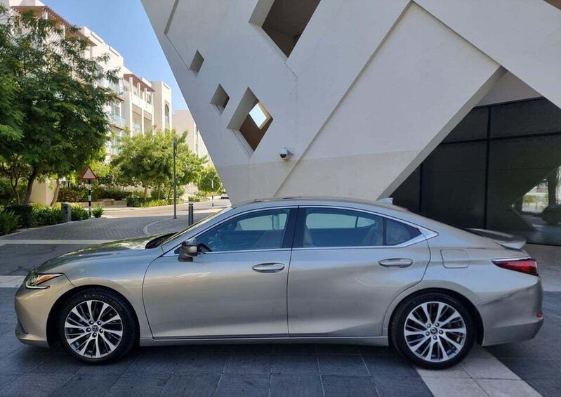 Un sedán plateado estacionado frente a un edificio moderno con formas geométricas y ventanas. 5