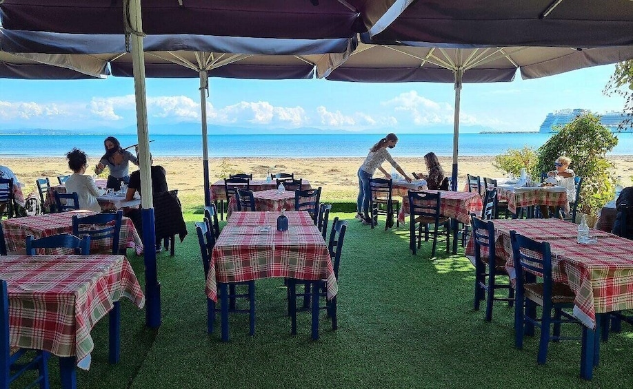 An outdoor dining area with tables and chairs, a grassy floor, and a view of the ocean. 5