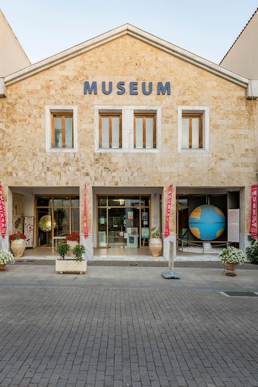 A museum building with a stone facade, large windows, and a globe display. 1