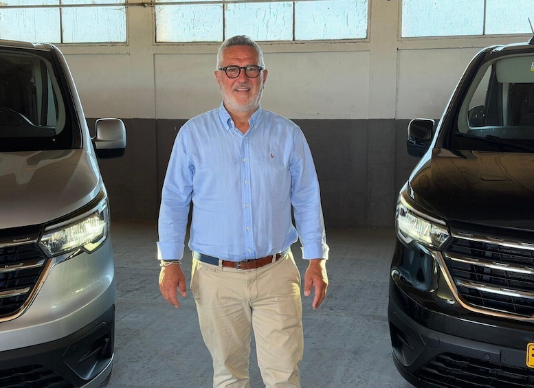 A man standing between two cars in a garage. 2