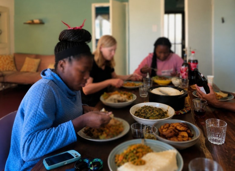 A group of people sitting at a table with various dishes, a bottle, and glasses. 3