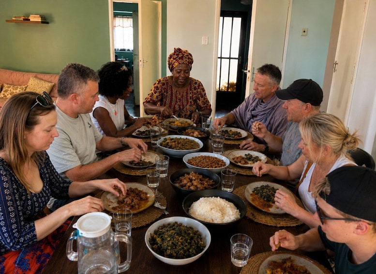 A group of people sitting around a table with various dishes and drinks. 1