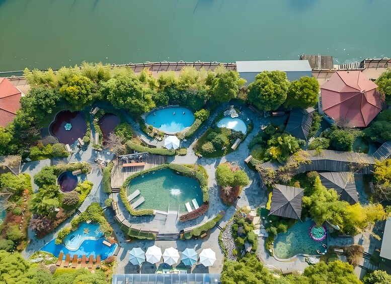 An aerial view of a resort with multiple swimming pools surrounded by lush greenery and trees. 1