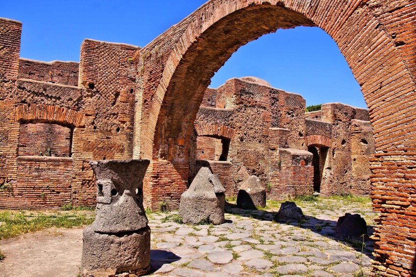 Ancient brick ruins with a large archway and stone pedestals. 4