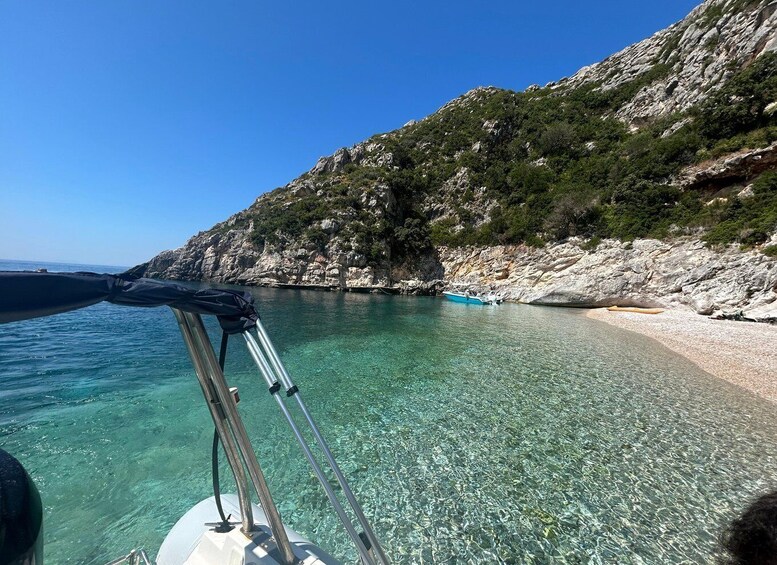 A clear turquoise sea, rocky coastline, and a boat with a clear canopy. 3