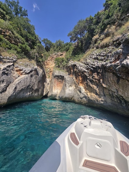 A boat navigating through a narrow waterway flanked by rocky cliffs and dense vegetation. 1