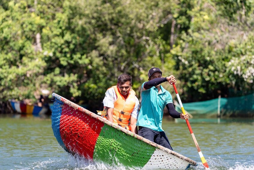 Two people rowing a colorful boat on a calm river. 4