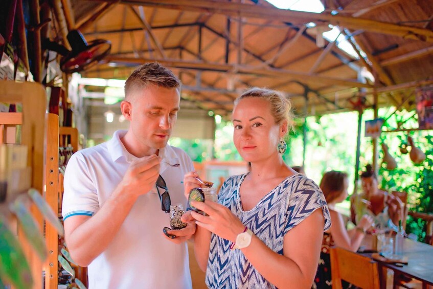 A man and a woman examining a jar of spices in a market setting. 2