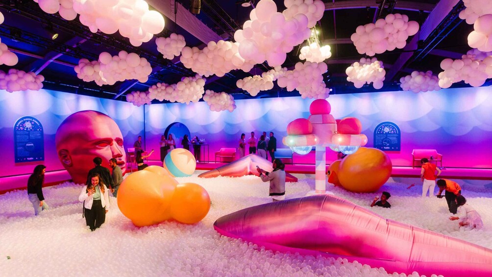 A colorful indoor play area with large balloons, a large inflatable duck, and people interacting with the environment. 1