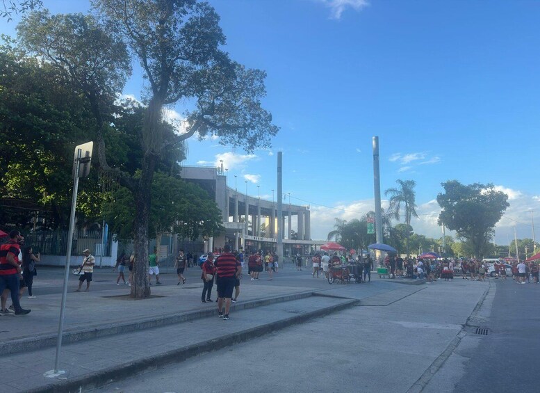 A busy urban square with people walking, a large tree, and a building with columns. 4