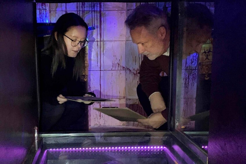 Two people examining a display case with a purple LED light strip. 3