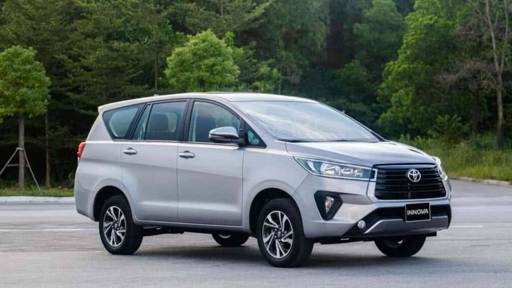 A silver SUV parked on a road with a forested background. 2