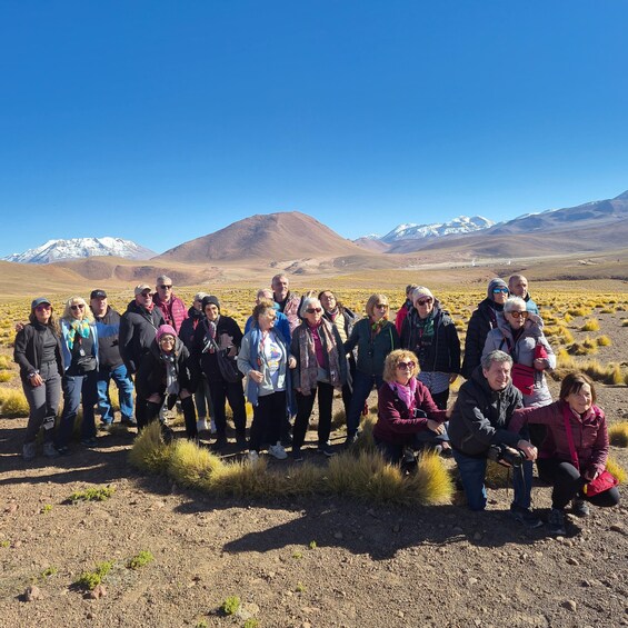 A group of people in a dry, grassy field with mountains in the background. 2