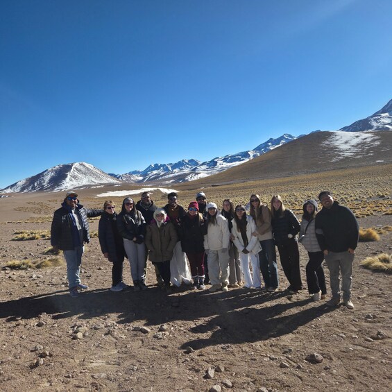 A group of people standing in a barren landscape with mountains in the background. 2