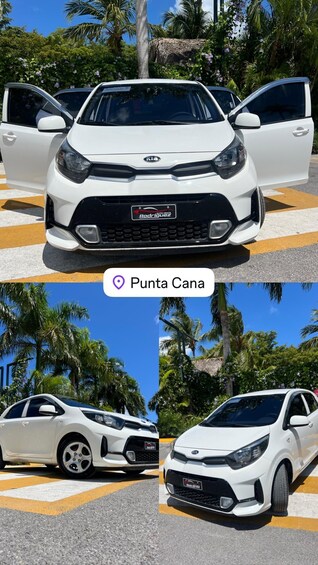 En vit Kia-bil med öppna dörrar, parkerad i en tropisk miljö med palmer och en klar himmel. 5