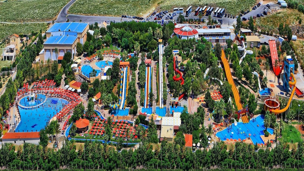 A water park with multiple slides, pools, and a large parking area. 2