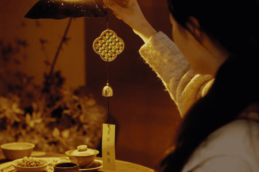 A person holding a traditional Chinese incense burner with a hanging ornament. 1