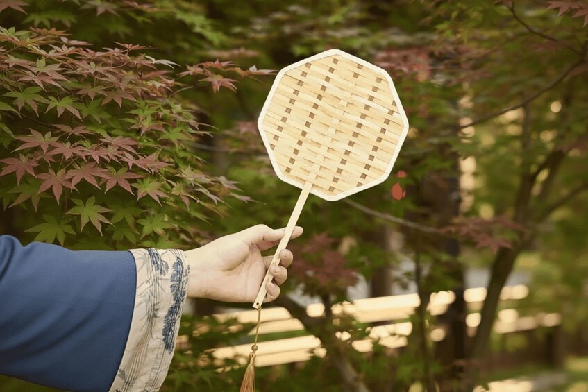 A hand holding a traditional Japanese fan with a woven pattern. 2