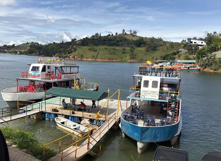 A river with boats docked at a pier, surrounded by greenery and hills. 4