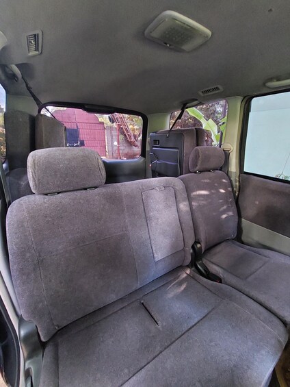 Interior de vehículo con asientos grises, espejo retrovisor y un compartimento de almacenamiento pequeño. 2