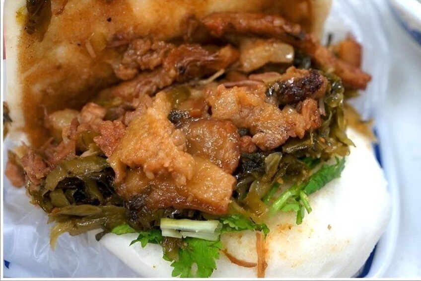 A close-up of a dish with shredded meat, greens, and a white base, possibly a type of wrap or sandwich. 3
