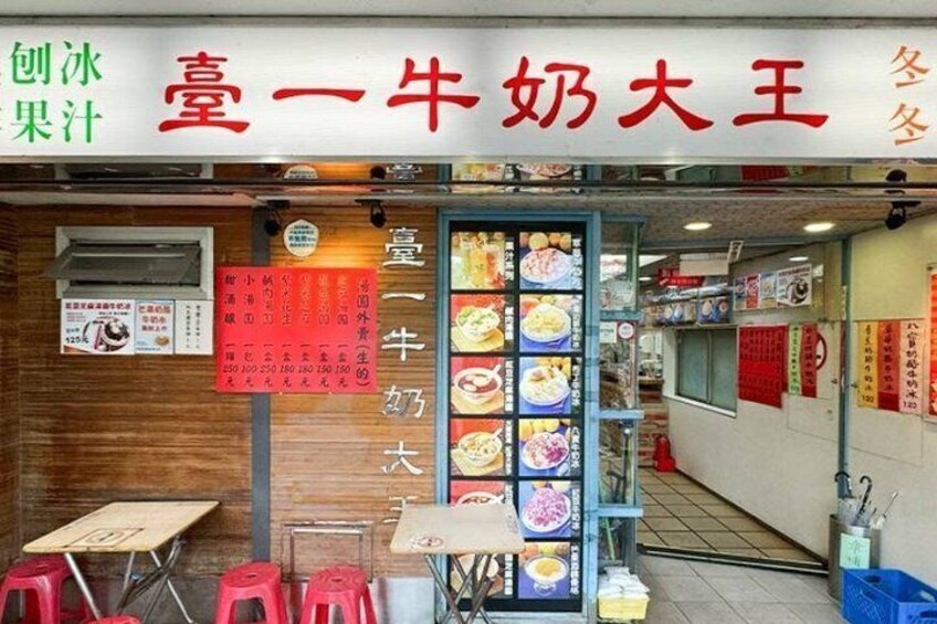 A restaurant with a menu board and stools outside. 5