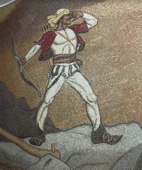 A mosaic of a figure in a red and white outfit, holding a bow and arrow, standing on a rocky surface. 3