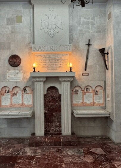 A stone wall with a coat of arms, a sword, and several plaques. 5