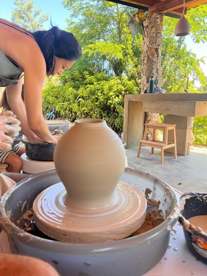A person shaping a clay pot on a pottery wheel. 2