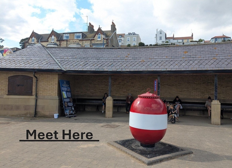 A red and white spherical sculpture in front of a building with a tiled roof and brick walls. 2