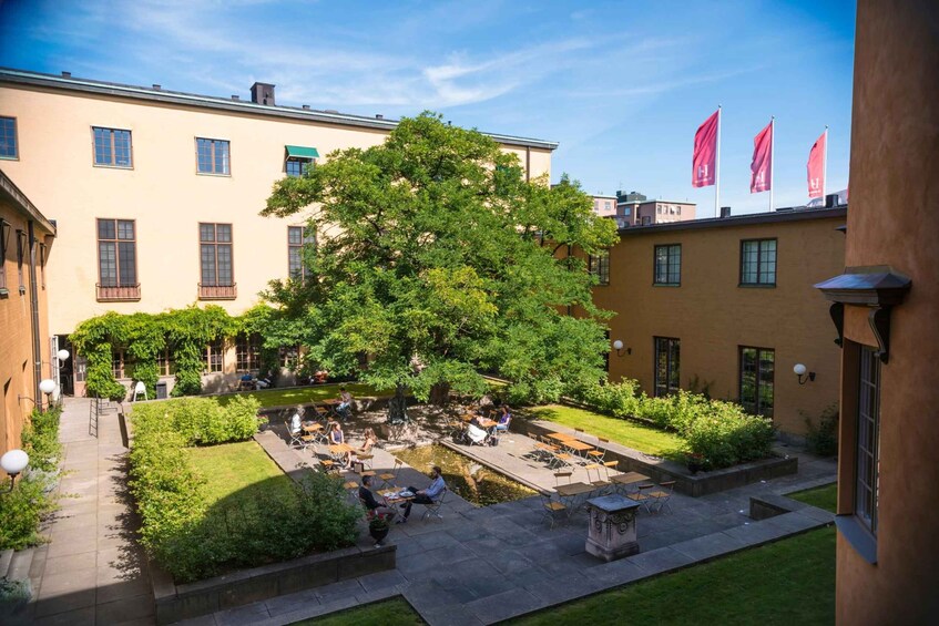 A courtyard with a large tree, outdoor seating, and a small pond. 5