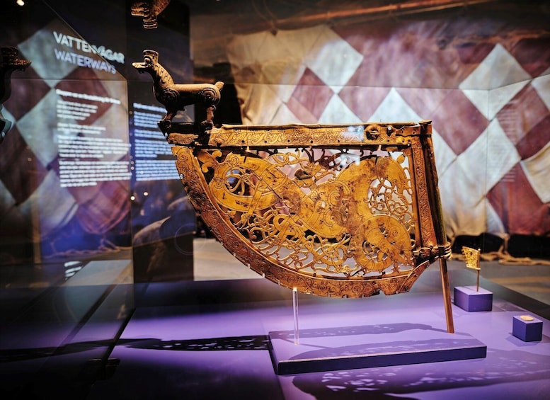 An ornate, golden artifact with intricate designs, displayed in a museum setting with informational panels in the background. 3