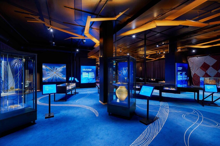 An indoor exhibition with glass display cases containing artifacts and information panels. 1