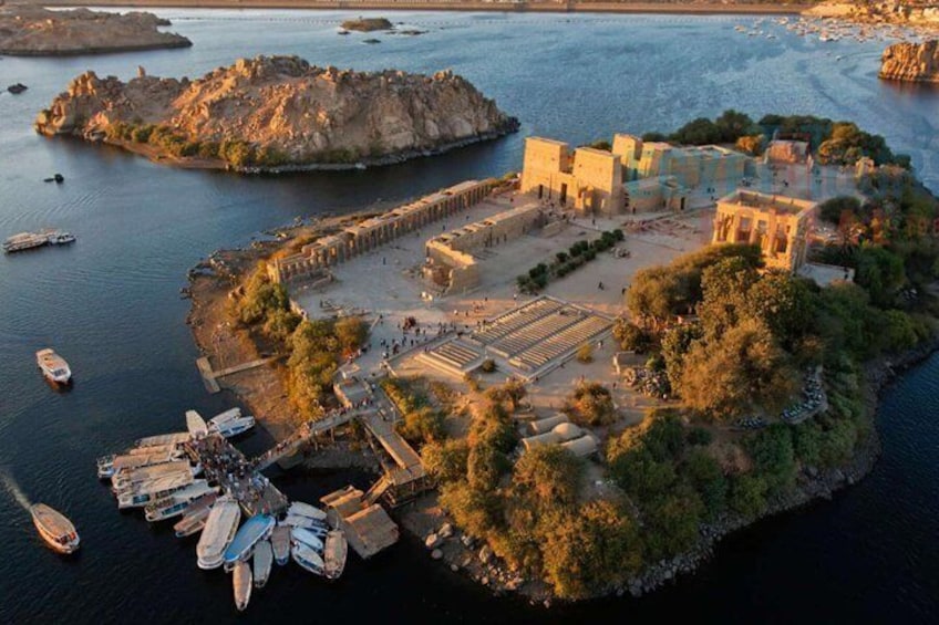 An aerial view of a coastal archaeological site with ruins, boats, and a rocky island. 4