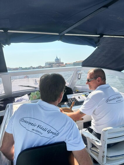 Two people on a boat with a cityscape in the background. 3