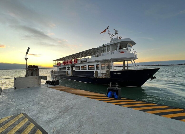 A ferry docked at a pier with a sunset in the background. 1