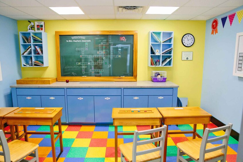 A classroom with a chalkboard, desks, chairs, and colorful storage units. 1