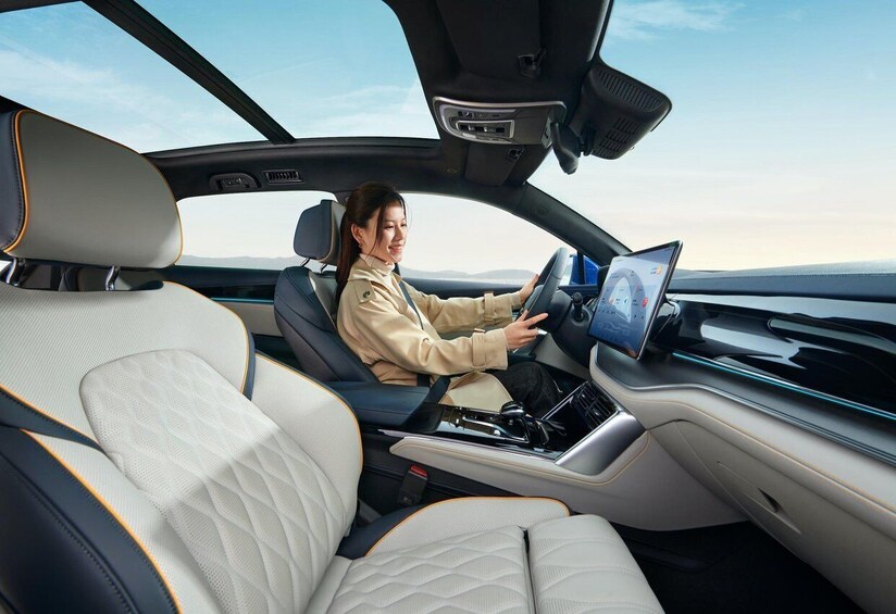 A woman driving a car with a digital dashboard and a sunroof. 2
